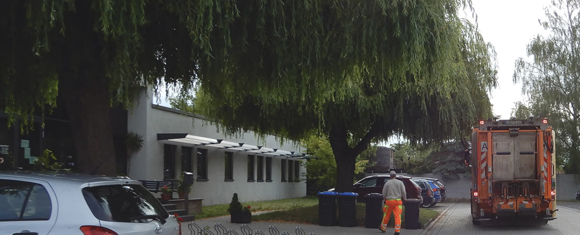 Foto: Sitz des EAW in der Karl-Fischer-Straße, Eingangsbereich mit Sammelfahrzeug bei der Behälterleerung