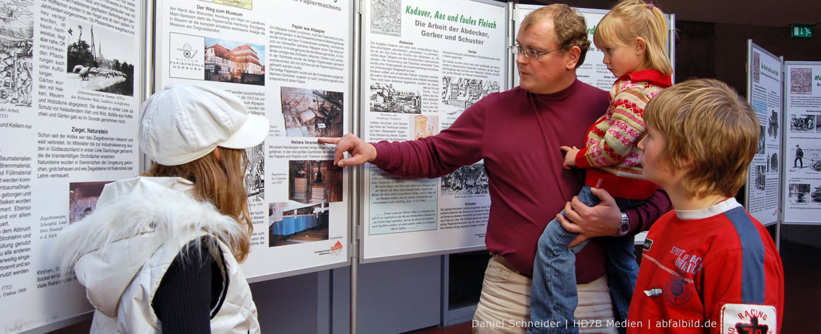 Foto: Ein Vater zeigt Kindern eine Ausstellung über Umweltschutz